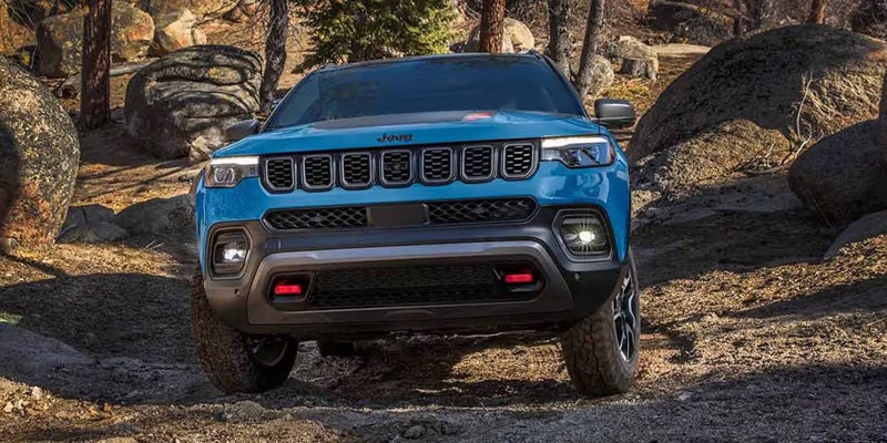 A blue jeep navigating a rocky trail, showcasing its rugged design and off-road capabilities.